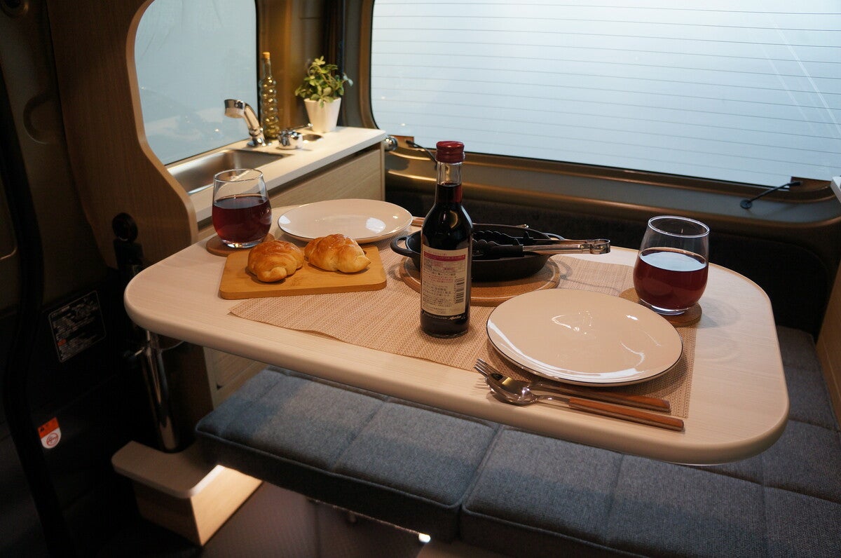 テーブルに料理やワイングラスを並べた車内での食事風景