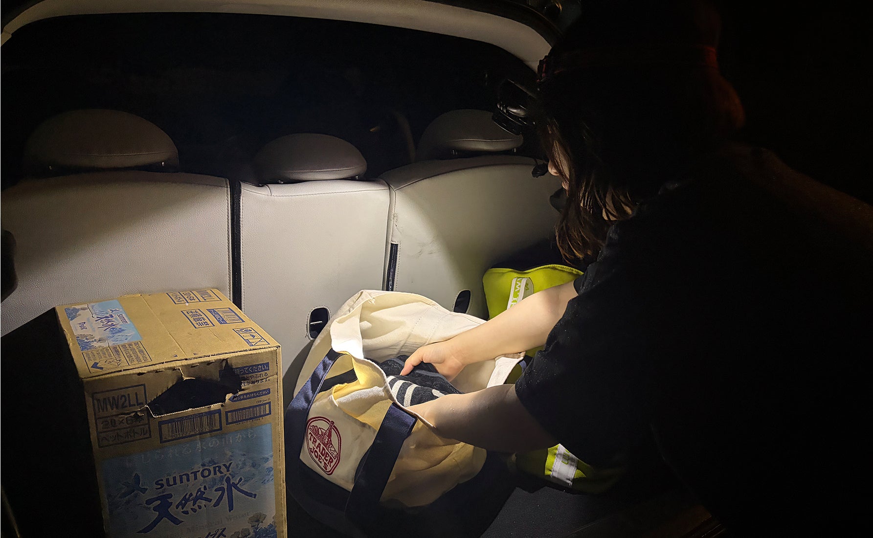 夜間に車内でLEDヘッドライトを頭に装着してラゲッジの荷物を取りだしている写真