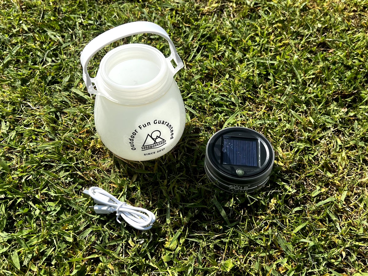芝生の上に並べられた「SOLR LANTERN minipod」の容器・LED・充電用ケーブルのセット