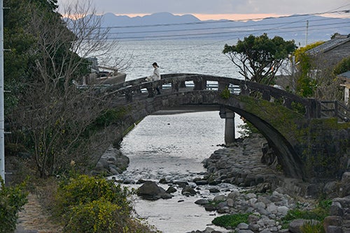 海の近くにかけられた石橋を渡る女性