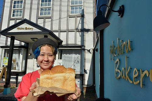 Michiru Bakeryの店先でパンを手にする比留間玲美さん。
