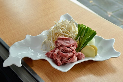 北海道の形をしたお皿にのった生肉と野菜