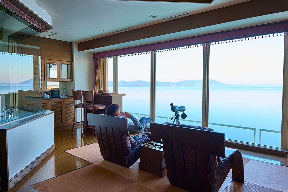 客室からサロマ湖を眺める男性