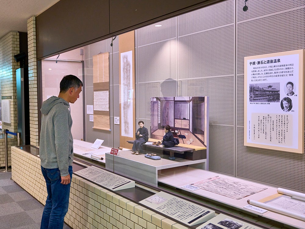 子規記念博物館の展示を見る男性