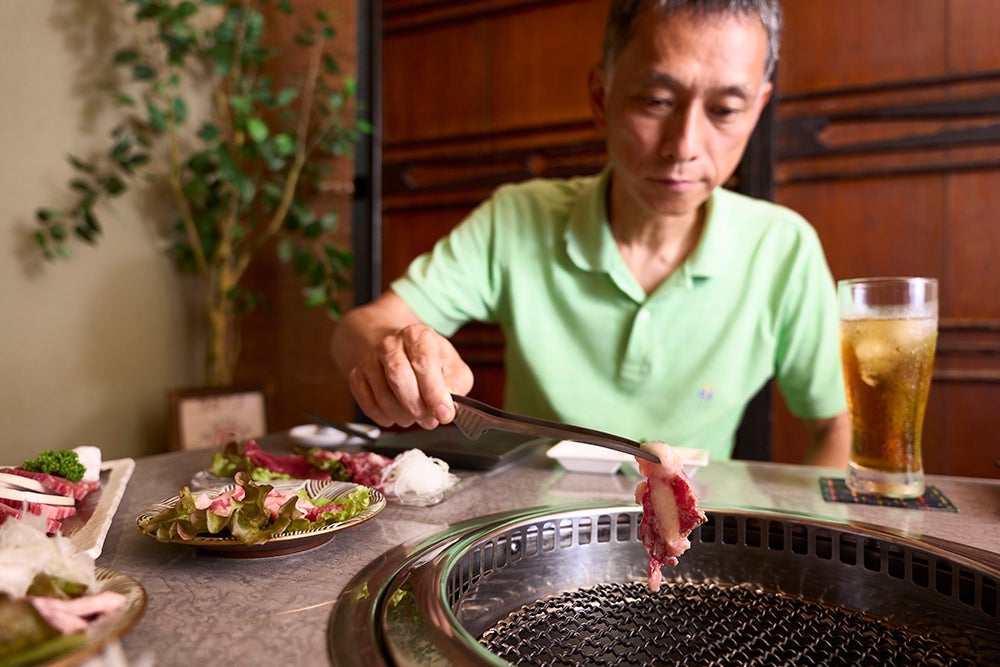 焼肉を焼く男性