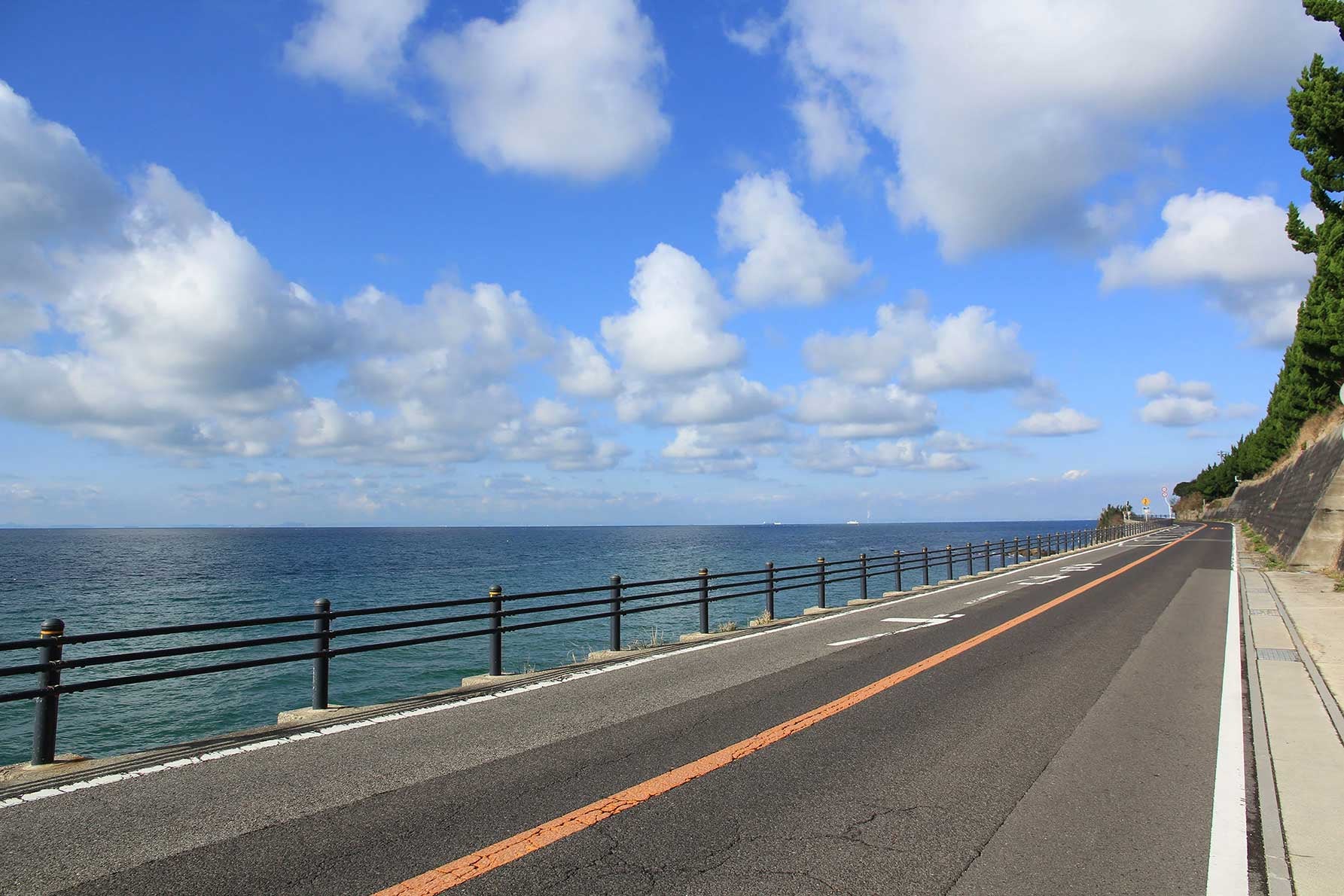 写真３ 明神岬近辺の道はガードレールも低く海辺を近く感じる