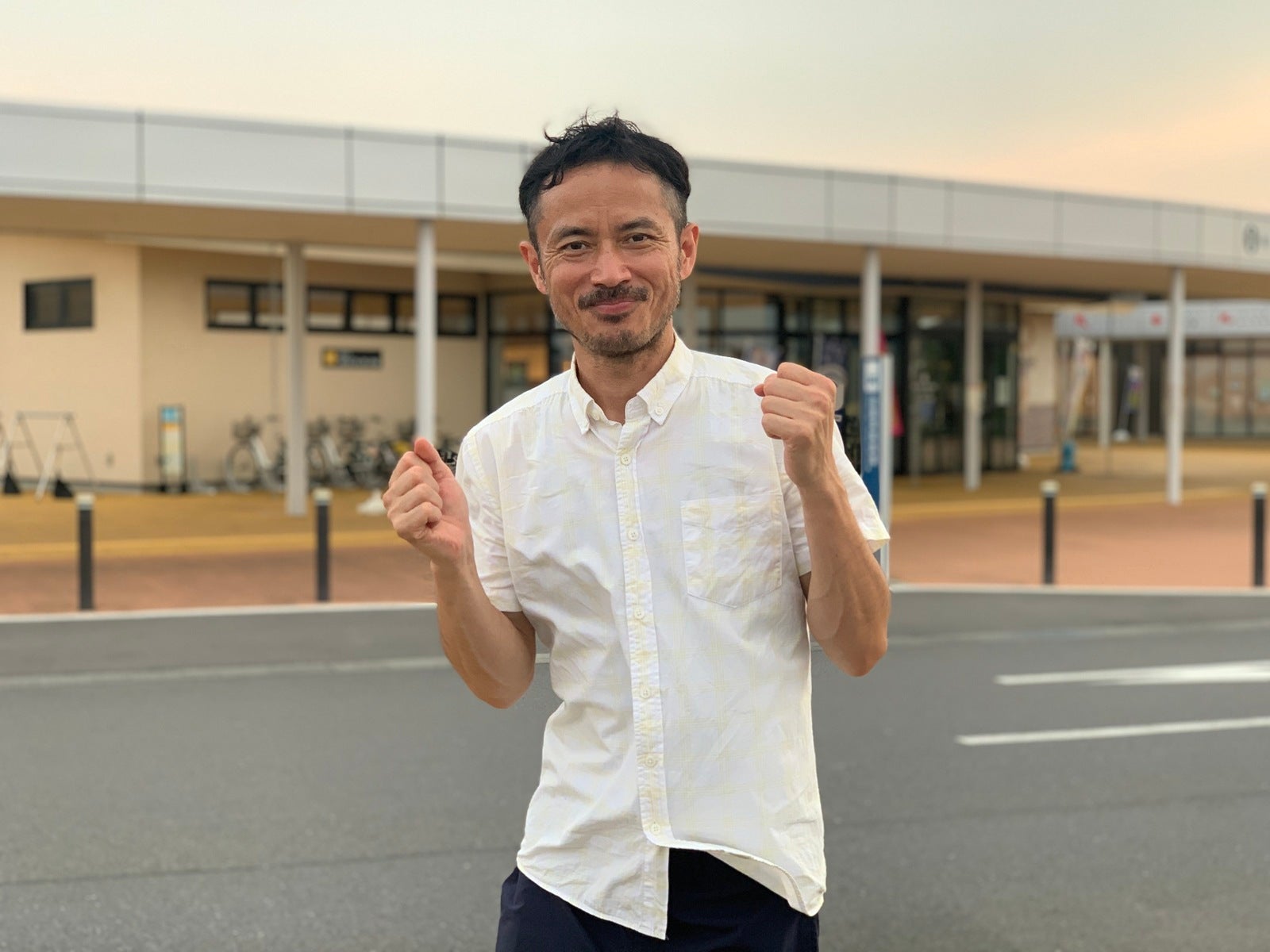道の駅の駐車場でポーズをとる男性