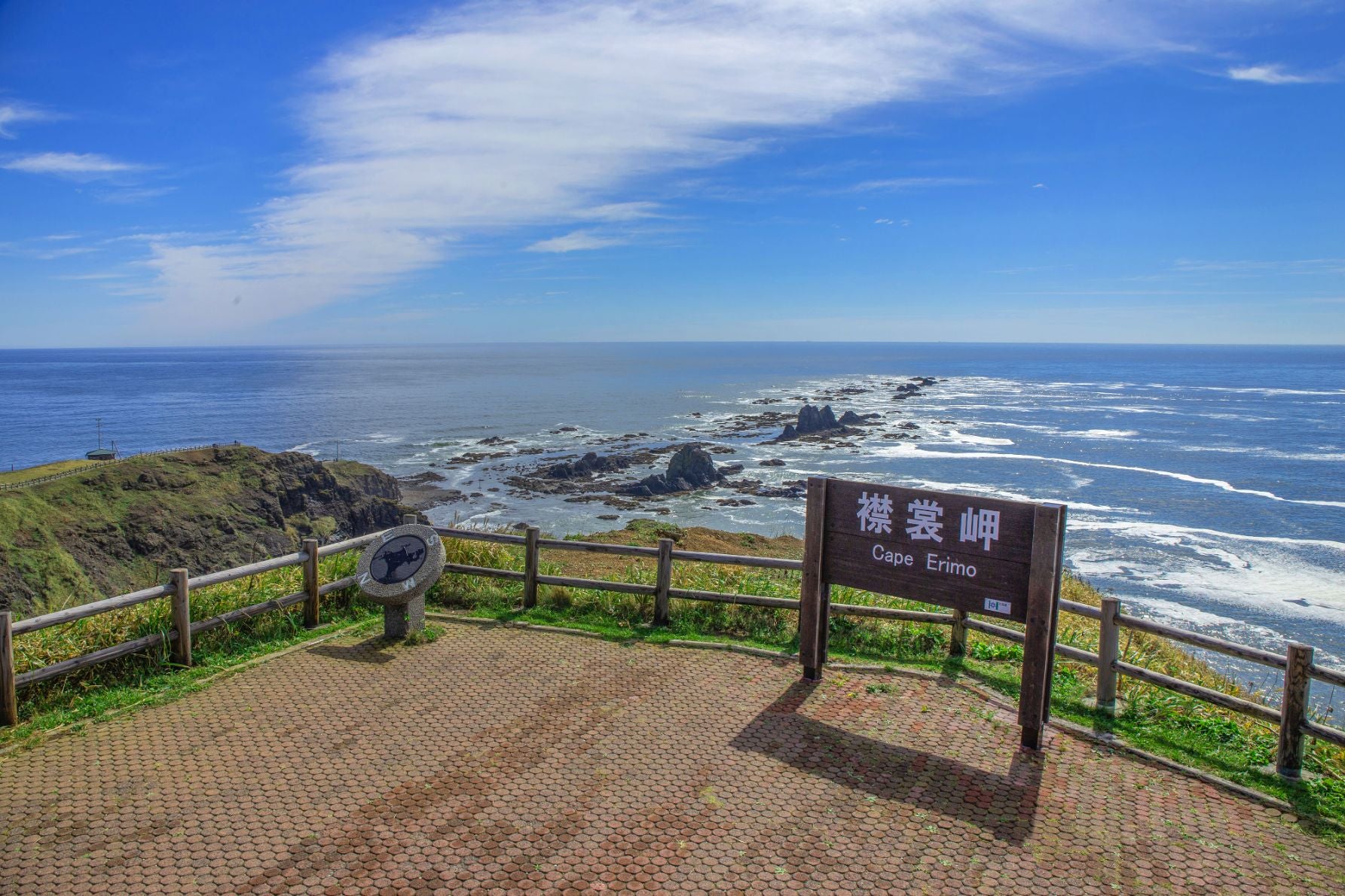 北海道えりも町・襟裳岬の展望風景。『襟裳岬』の木製看板と太平洋に広がる岩礁海岸、情報案内板が設置された観光スポット