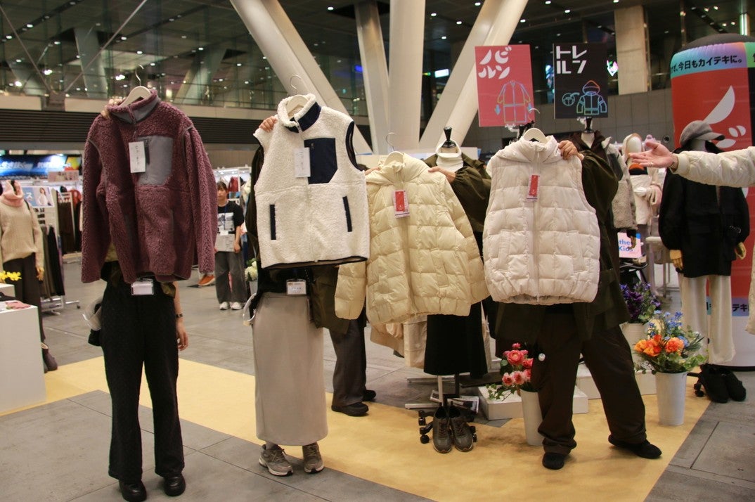 フリースとダウンジャケットを手に持ち掲げる4名