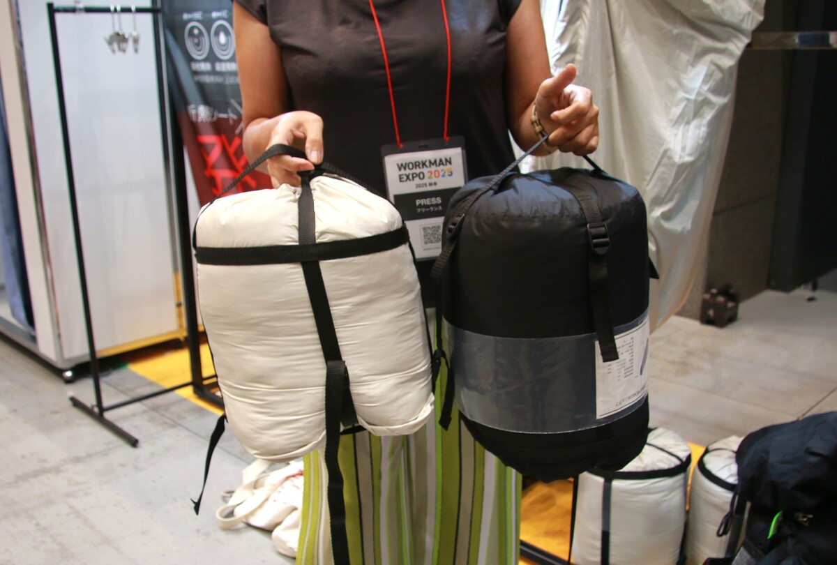 収納袋に入った2つの寝袋を手に持つ