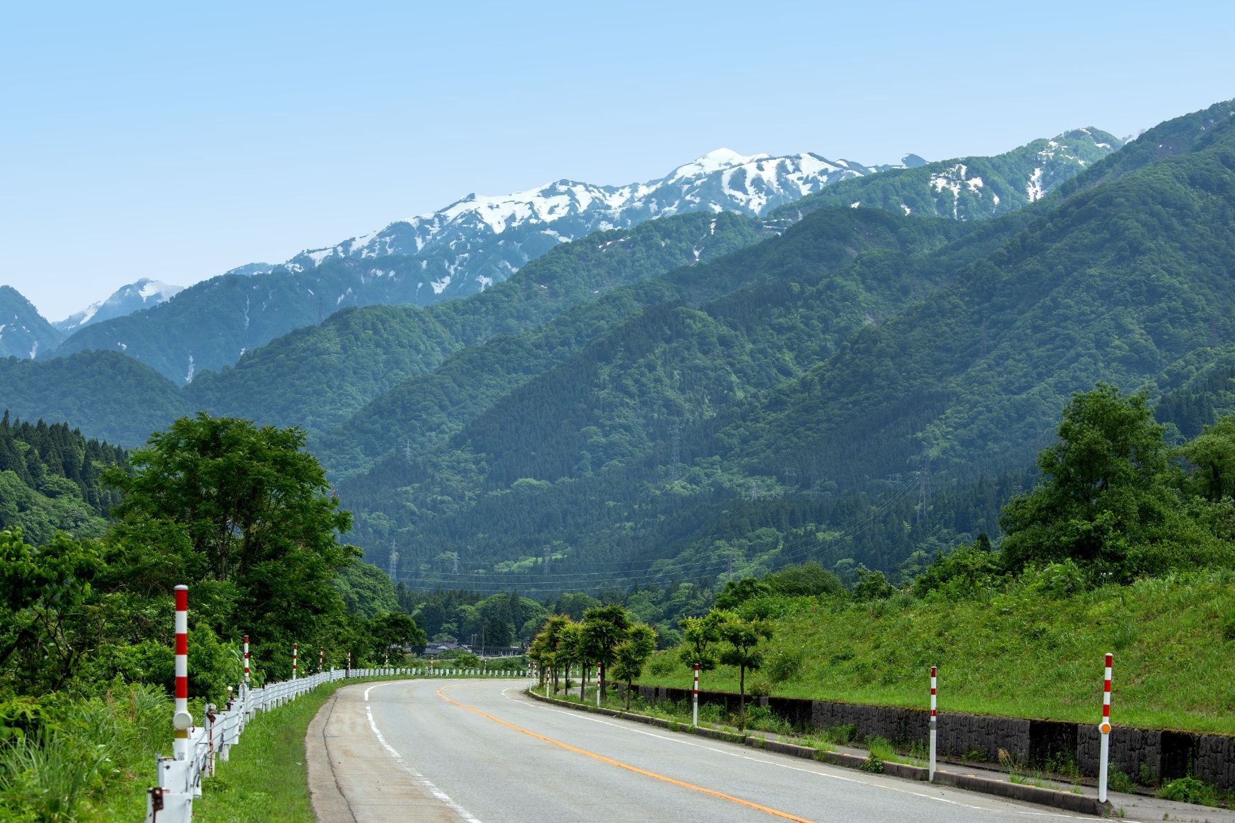 富山県黒部峡谷を背景に、緑に包まれた山々と曲がりくねる県道14号が続く絶景ドライブルート
