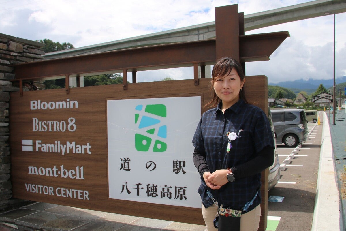 道の駅の看板前に立つ女性