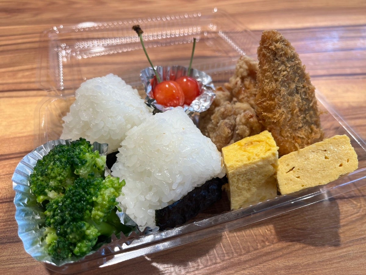 プラ容器に入ったおにぎりと玉子焼きなどの弁当写真