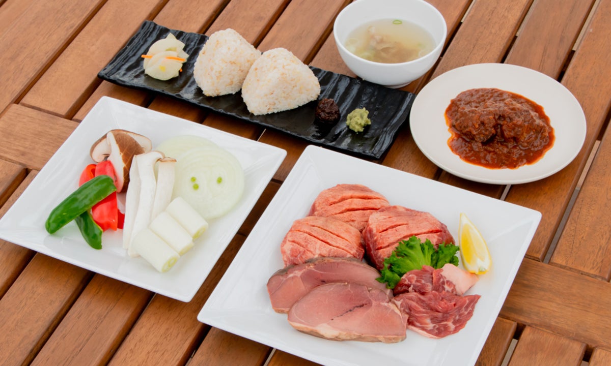 BBQ用の牛タン、野菜、おにぎりなどが各皿に盛られた風景