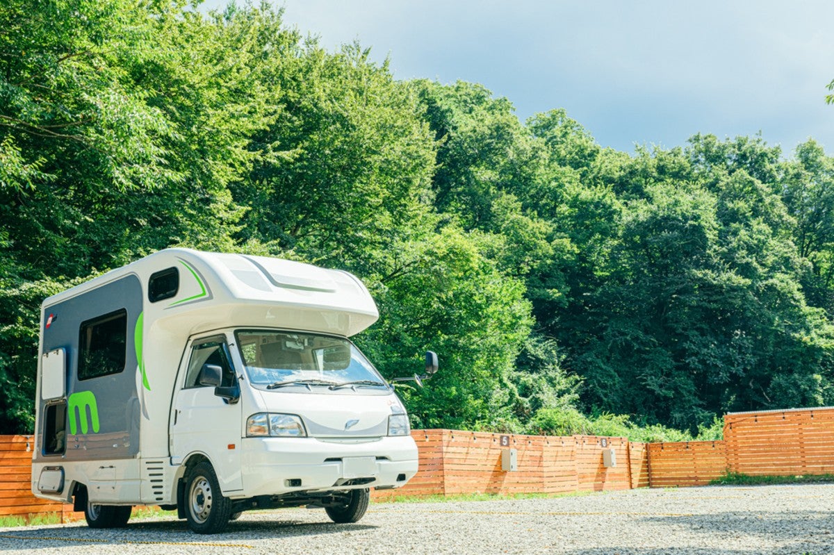 森をバックにした駐車場に駐車しているキャンピングカー