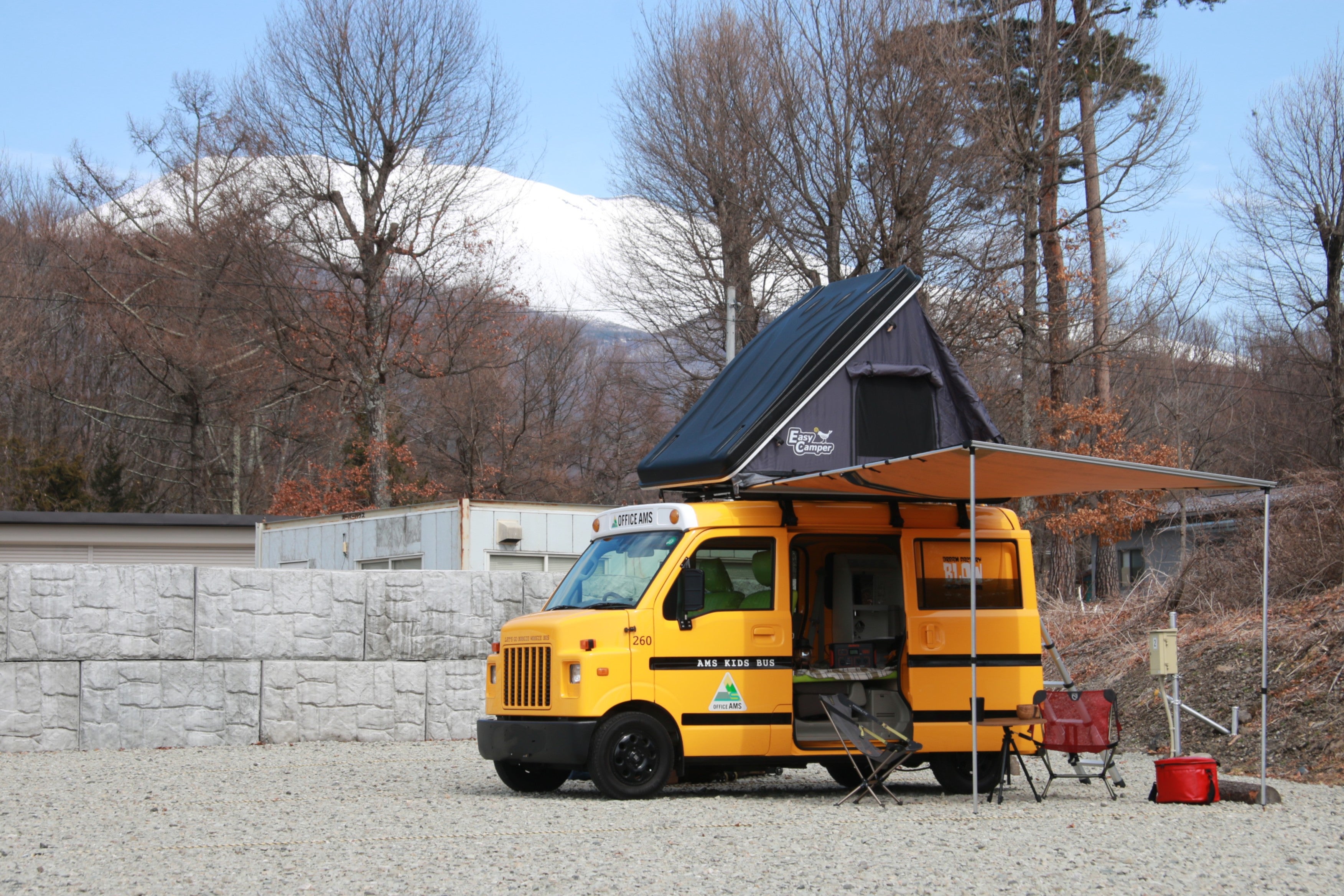 軽キャンピングカーのサイドオーニングを展開し、テーブルとチェアを広げた風景