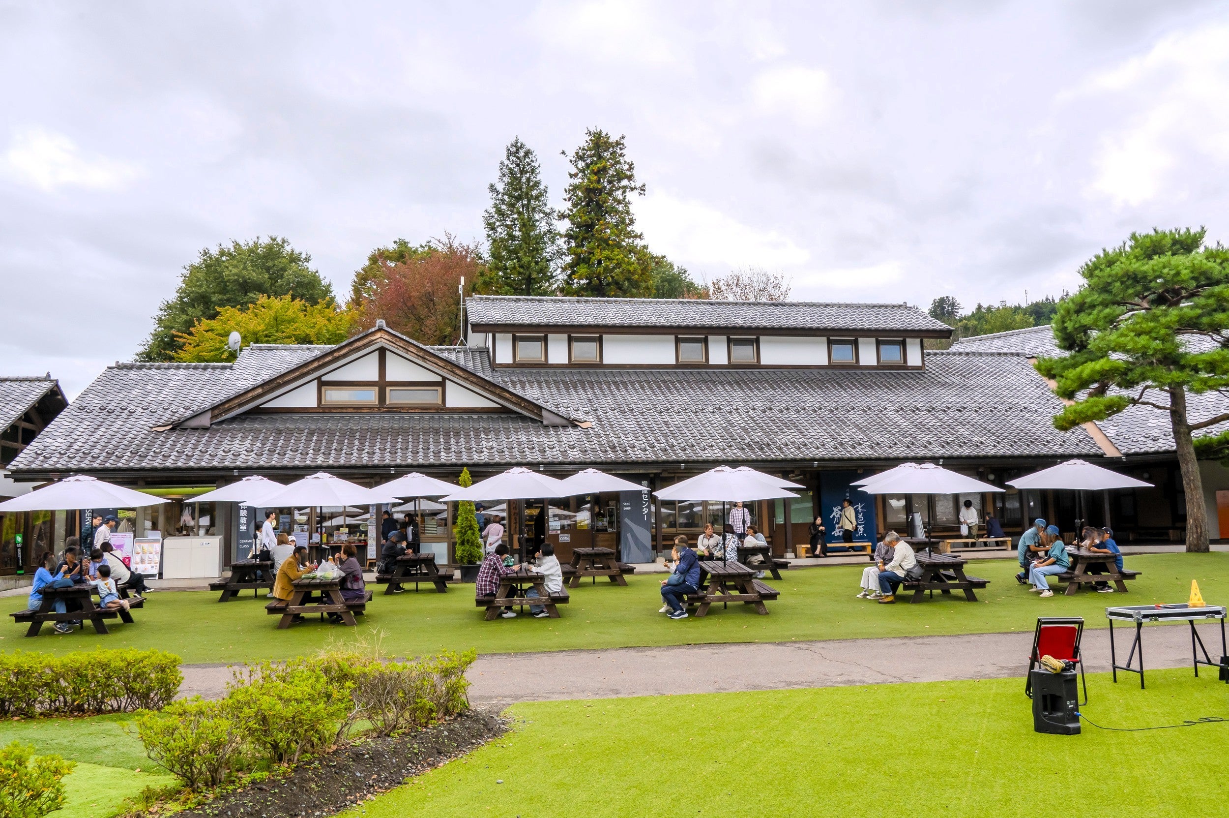 道の駅建物外観とその前に並ぶパラソルとテーブル＆チェアの風景
