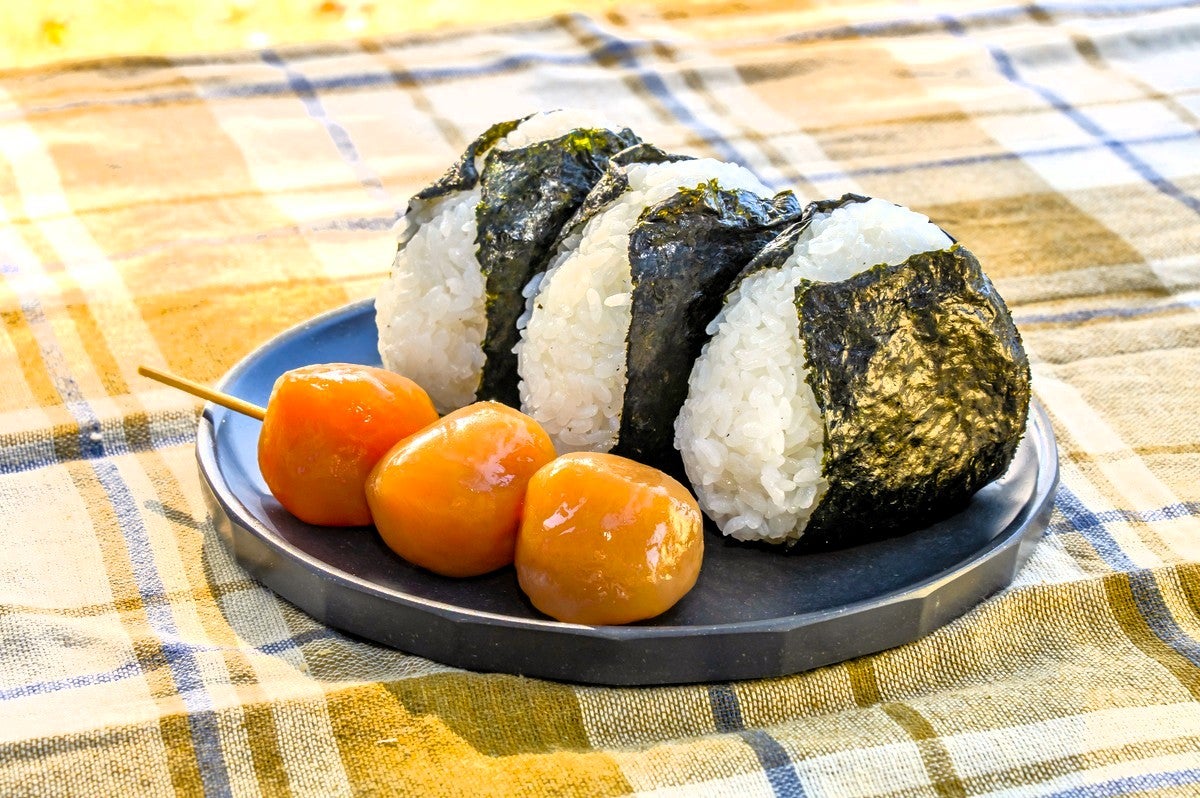 皿にのせた３つのおにぎりと玉こんにゃく串