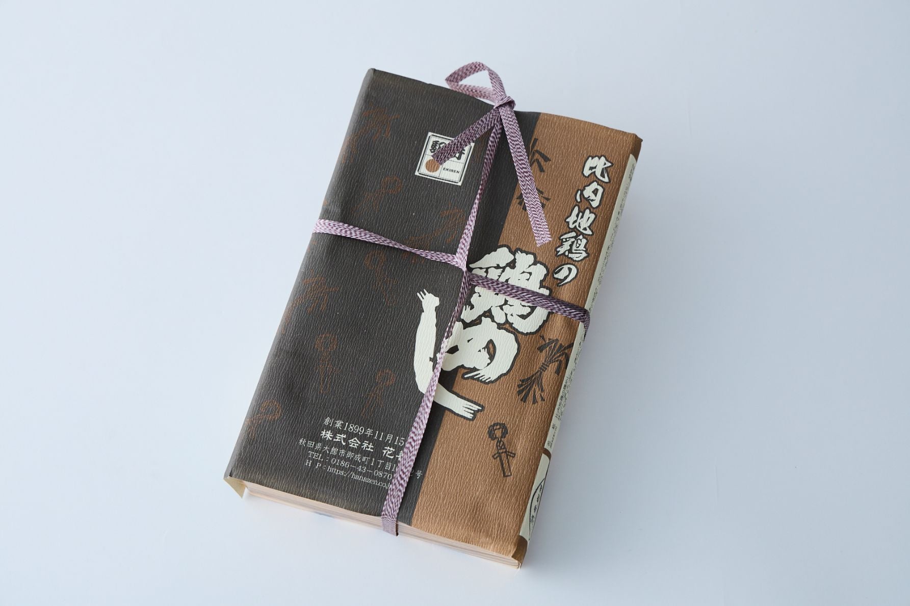 昔ながらの駅弁の雰囲気を演出する、十字にかけられたひものパッケージの比内地鶏の鶏めし