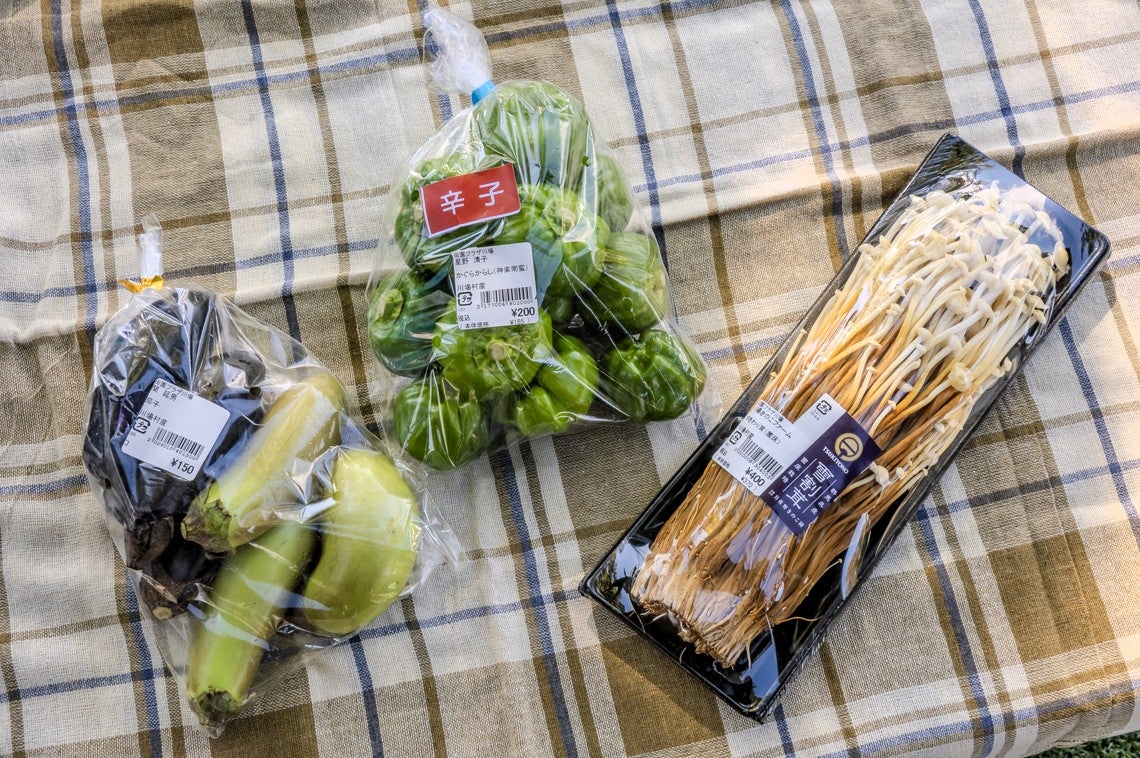 ビニール袋のままテーブルの上にのせた雪割茸、かぐら辛子、なす
