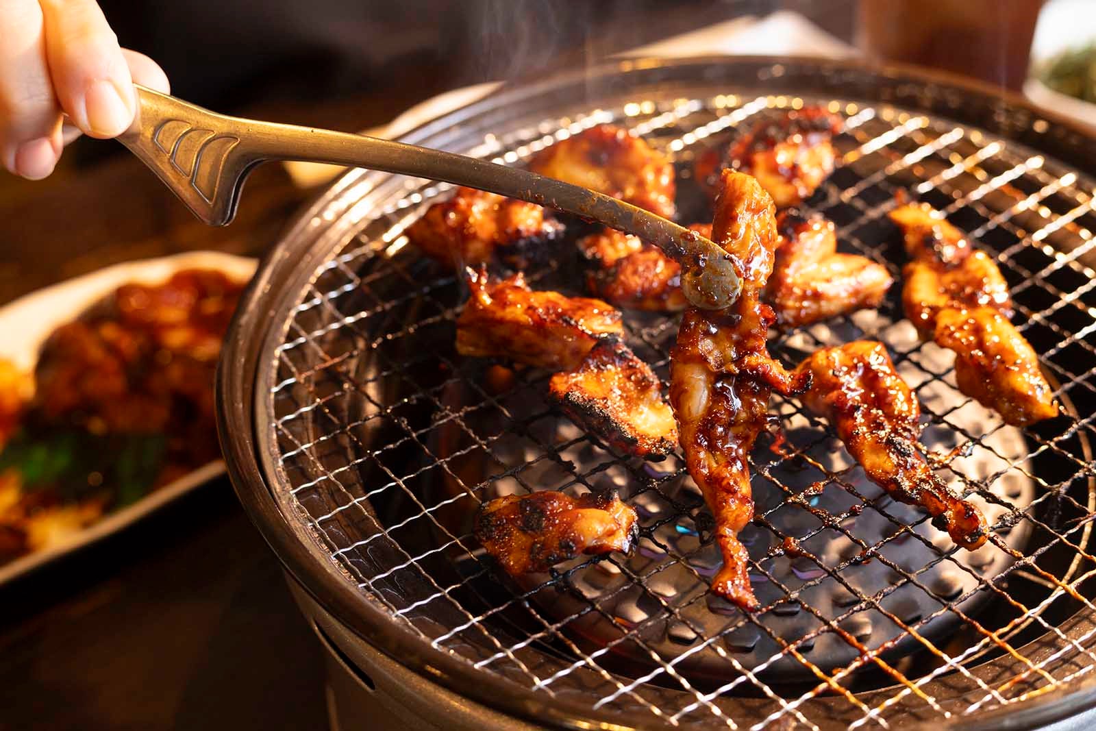 とり乃屋の味噌味鶏焼き。甘辛い味噌ダレで和えた鶏肉を七輪で焼く様子