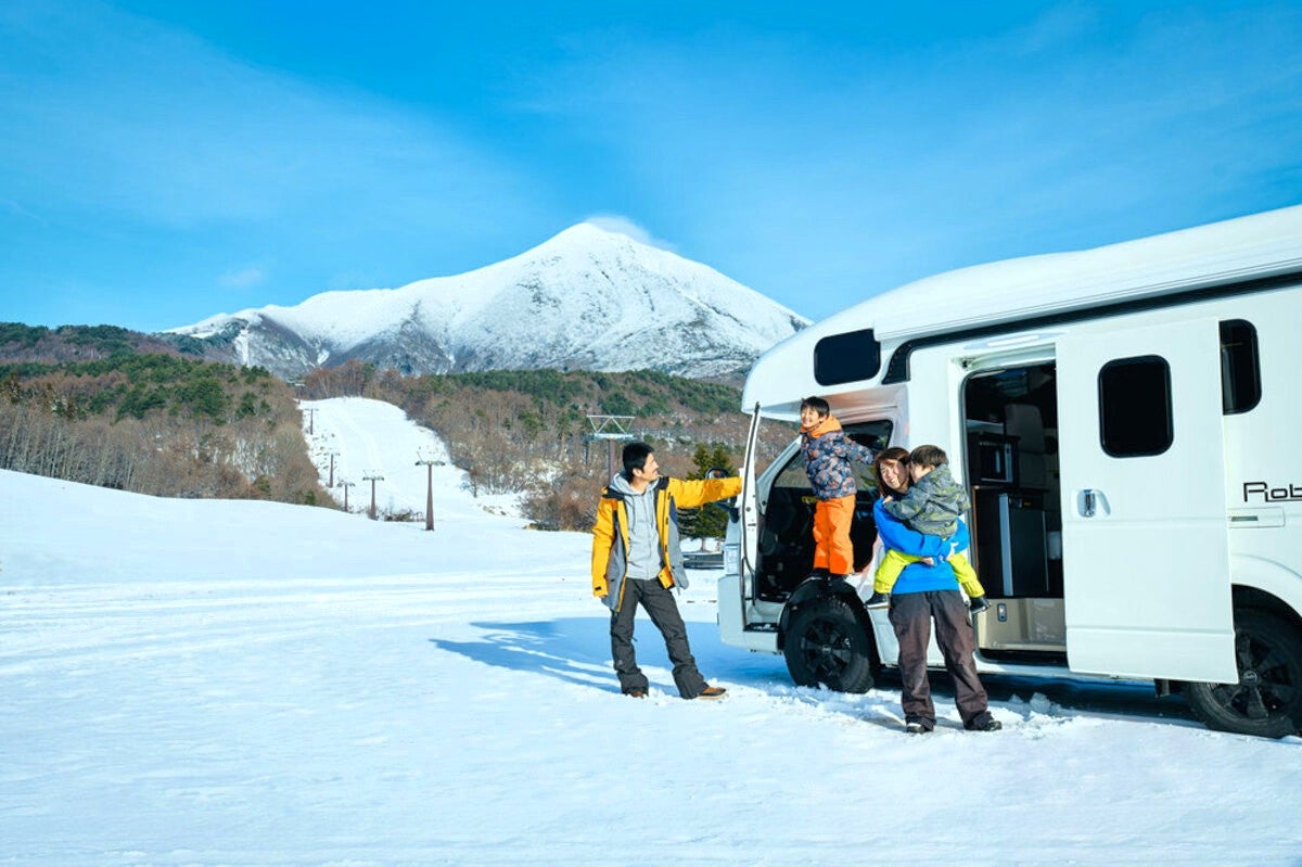 スキー場ゲレンデ前のRVパークでキャンピングカーから降り立つ家族