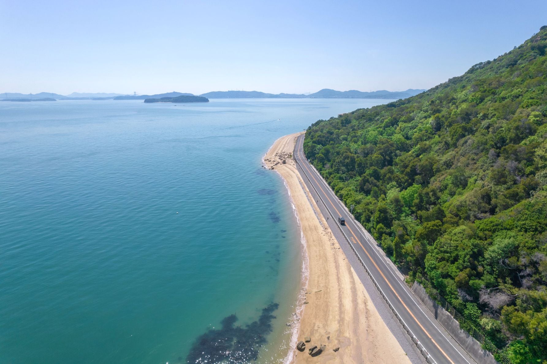 瀬戸内海の海岸線に沿って伸びる王子マリンロード430と緑の山肌