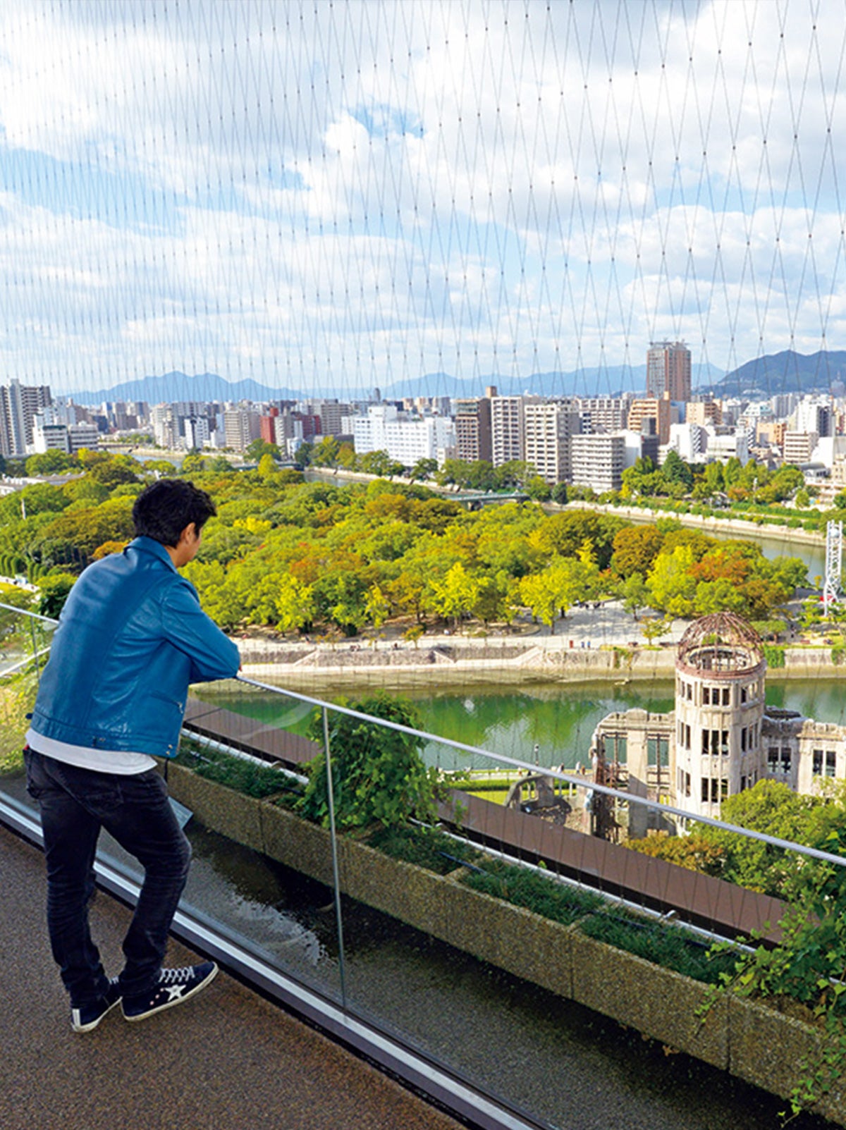 おりづるタワーの展望台から広島の街を見渡す小澤征悦氏