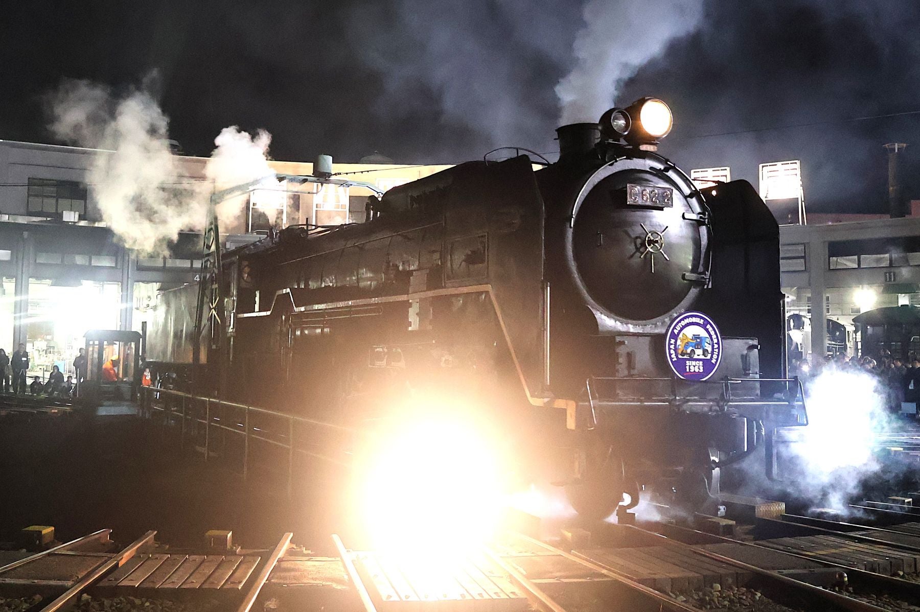 夜間の京都鉄道博物館で、ライトアップされた蒸気機関車が転車台で回転する迫力満点の実演シーン。