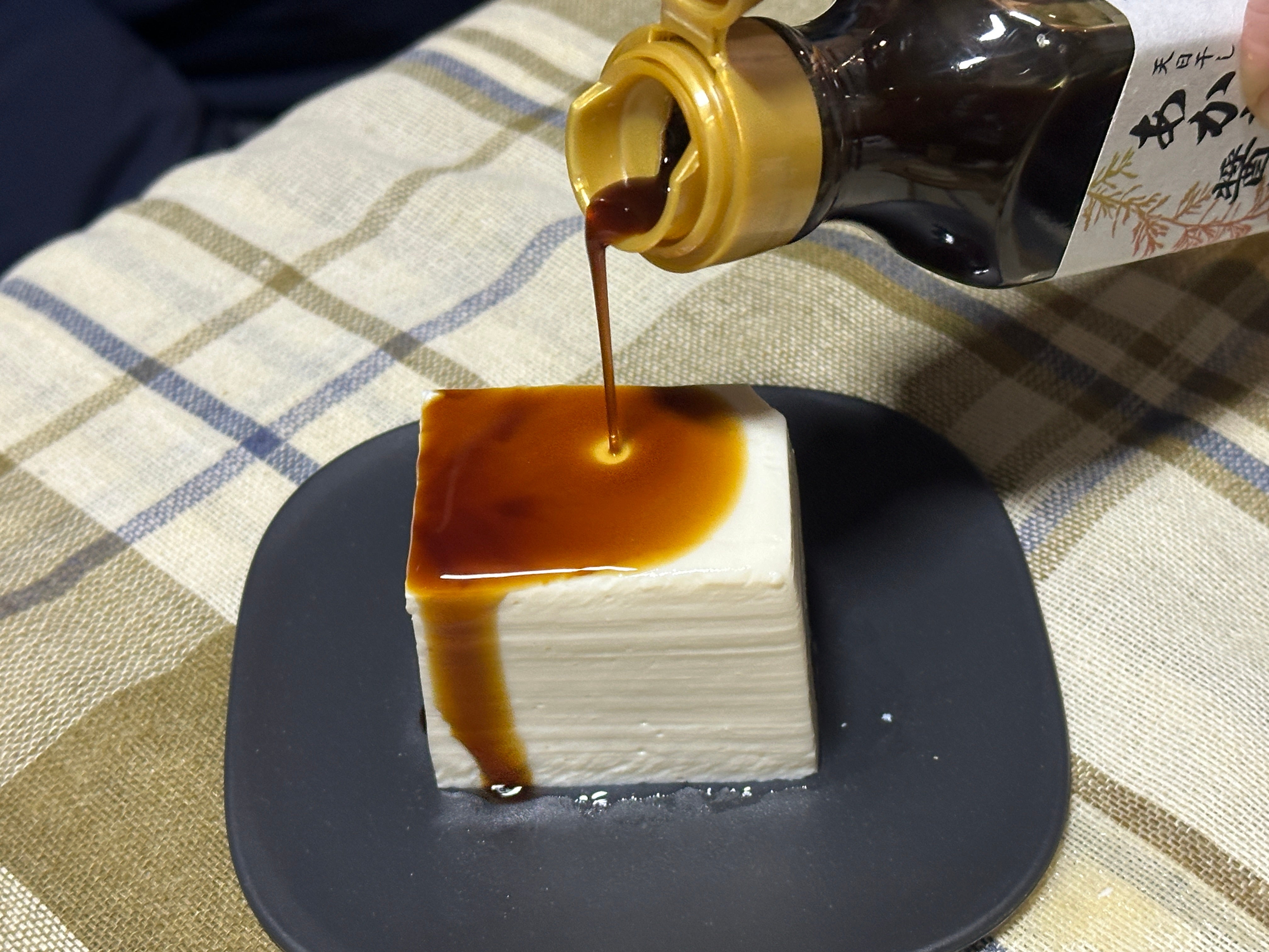 角切りした豆腐に醤油をかけている写真