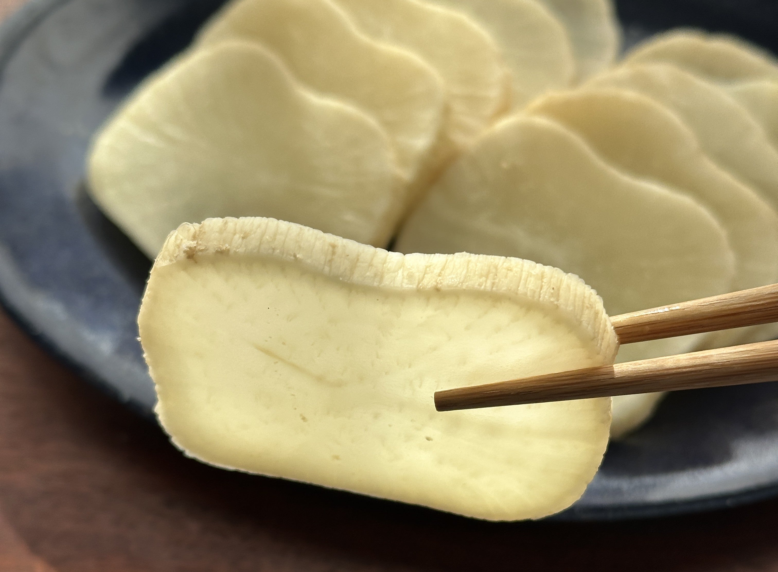 切って皿に載せたたくあんと1枚箸あげしている写真