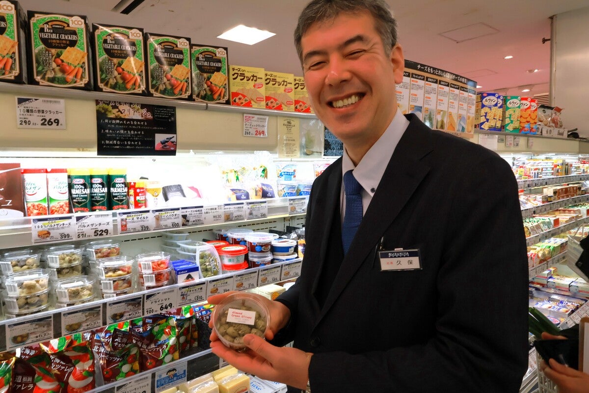 スーパーの商品を手に取り笑顔の男性スタッフ