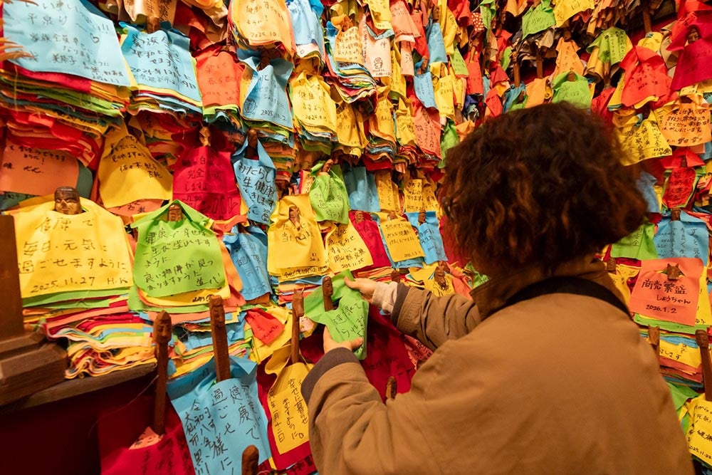 願い事が書かれた色とりどりの布に包まれたオシラサマの木像