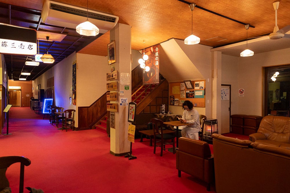 歴史を感じる赤い絨毯とレトロな照明が美しい藤三旅館のロビー