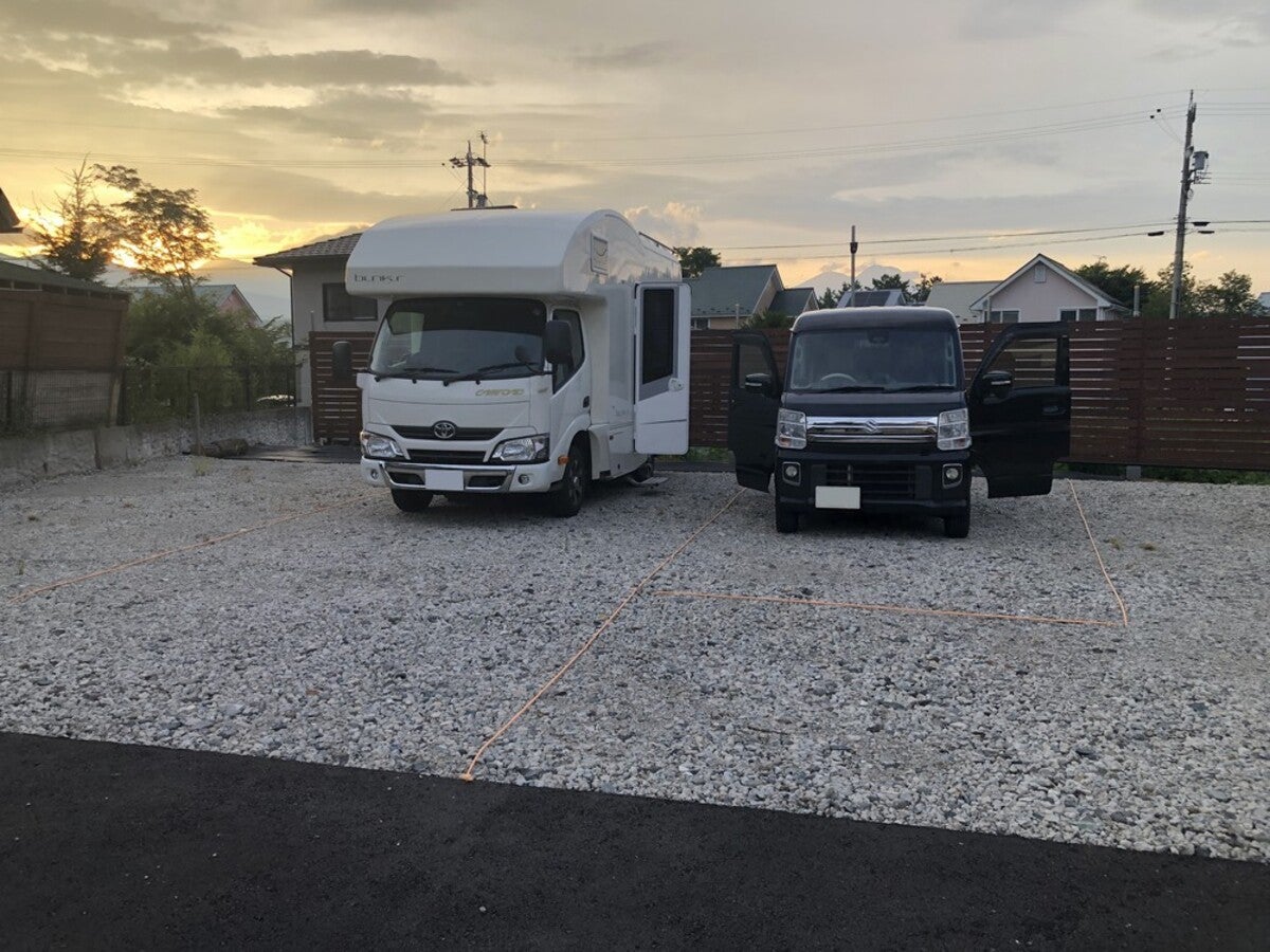 砂利敷きの駐車場に駐車する2台のクルマ