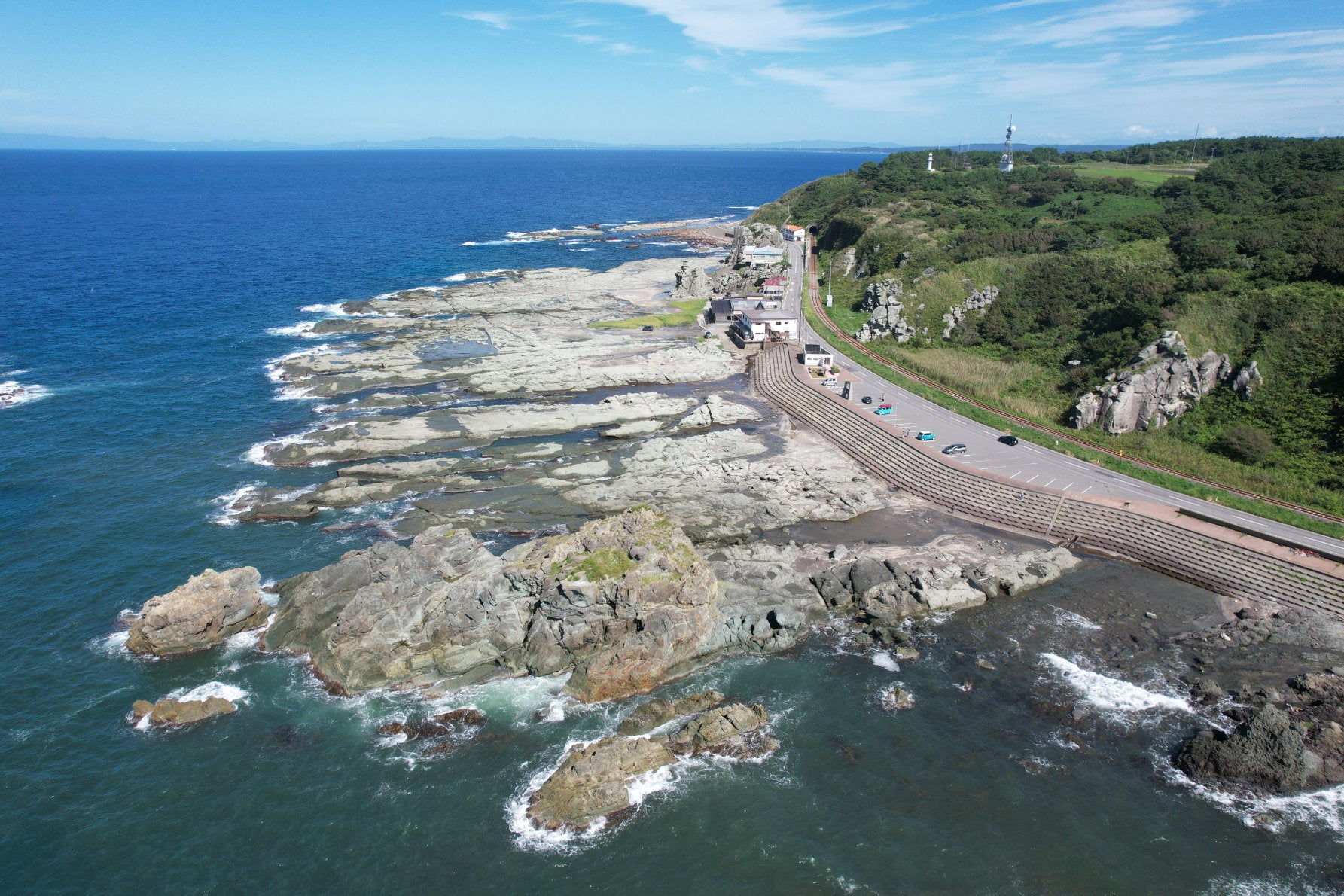 ALT 荒々しい自然の造形美の千畳敷海岸は、大間越街道の人気観光スポットだ。隆起した岩棚と「かぶと岩」などと名付けられた奇岩が続く。そのすぐそばを五能線と道路が並走している