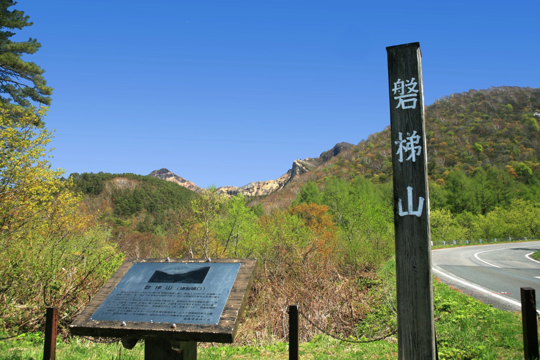 ALT 南側の穏やかな湖の景色から一転、「磐梯山（爆裂噴口）」の解説板と木柱の奥に見えるのは、大噴火で山体崩壊を起こした生々しい火口壁だ