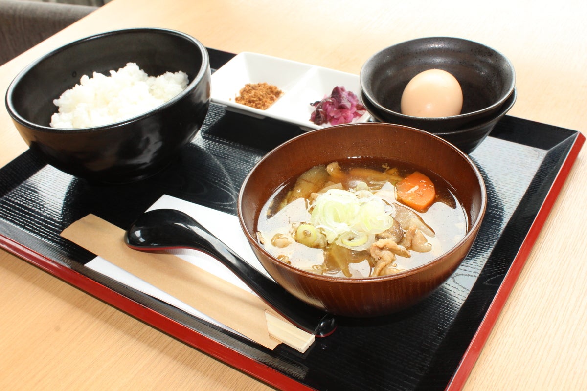 トレーに載った豚汁、ご飯、生卵の朝定食