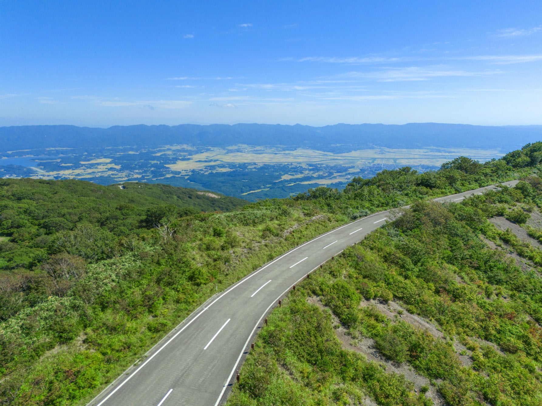 ALT 尾根つたいをダイナミックに駆け抜ける大佐渡スカイラインの道路。緑豊かな大自然に囲まれた美しいカーブの先には、遥か下に広がる平野部が一望できる
