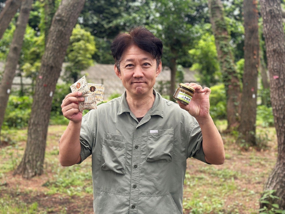 クッキーとふき味噌の瓶を手に持ち微笑む男性