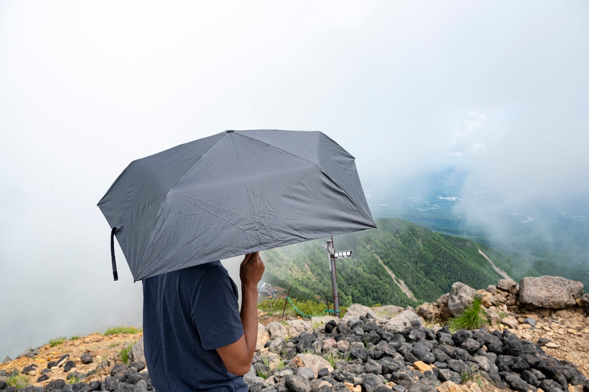 登山で傘をさしている男性