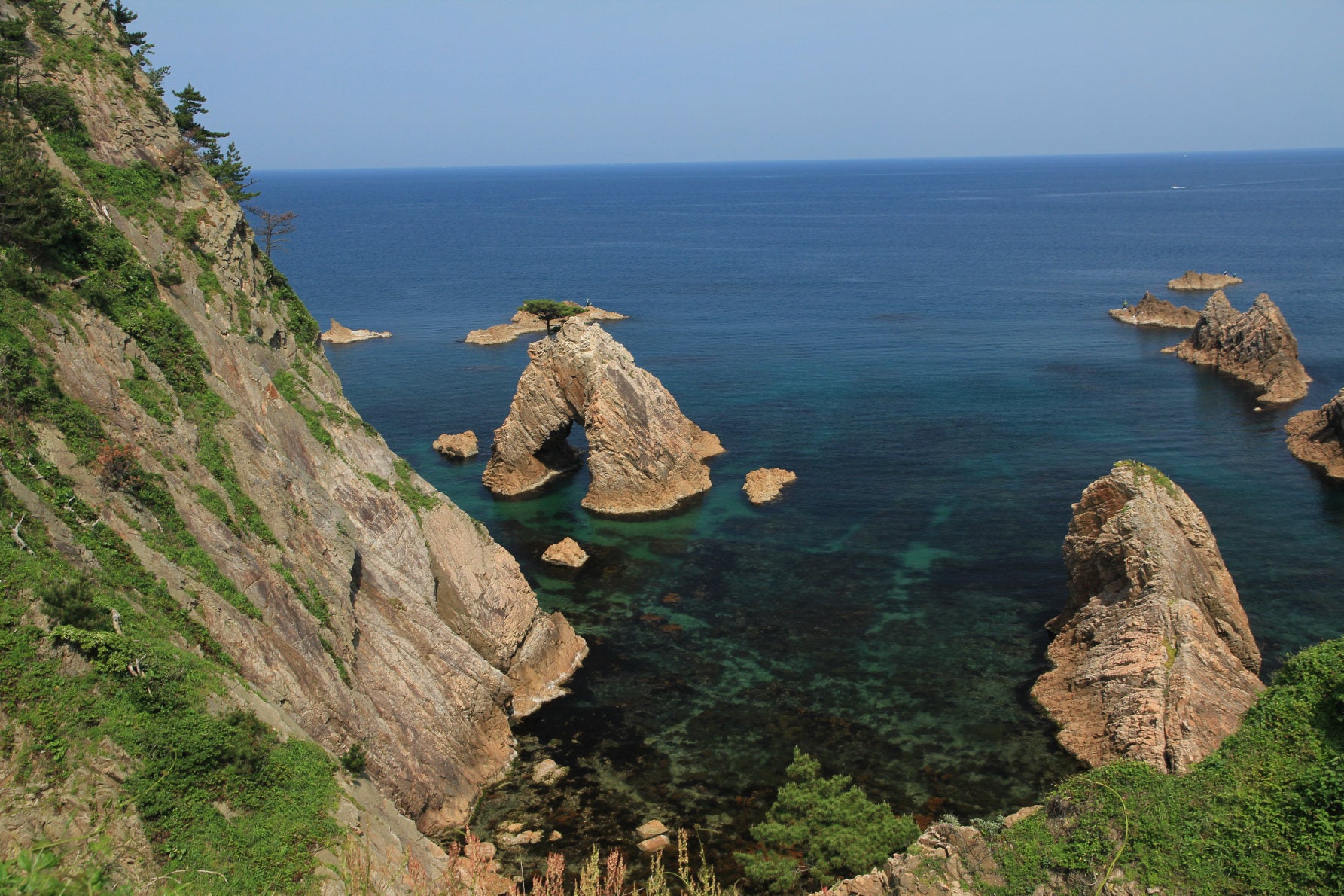 高さ約10mの花崗岩（かこうがん）にぽっかりと穴が開いた「千貫松島」。岩の上に1本の松が構える、浦富海岸を代表するシンボル的景観