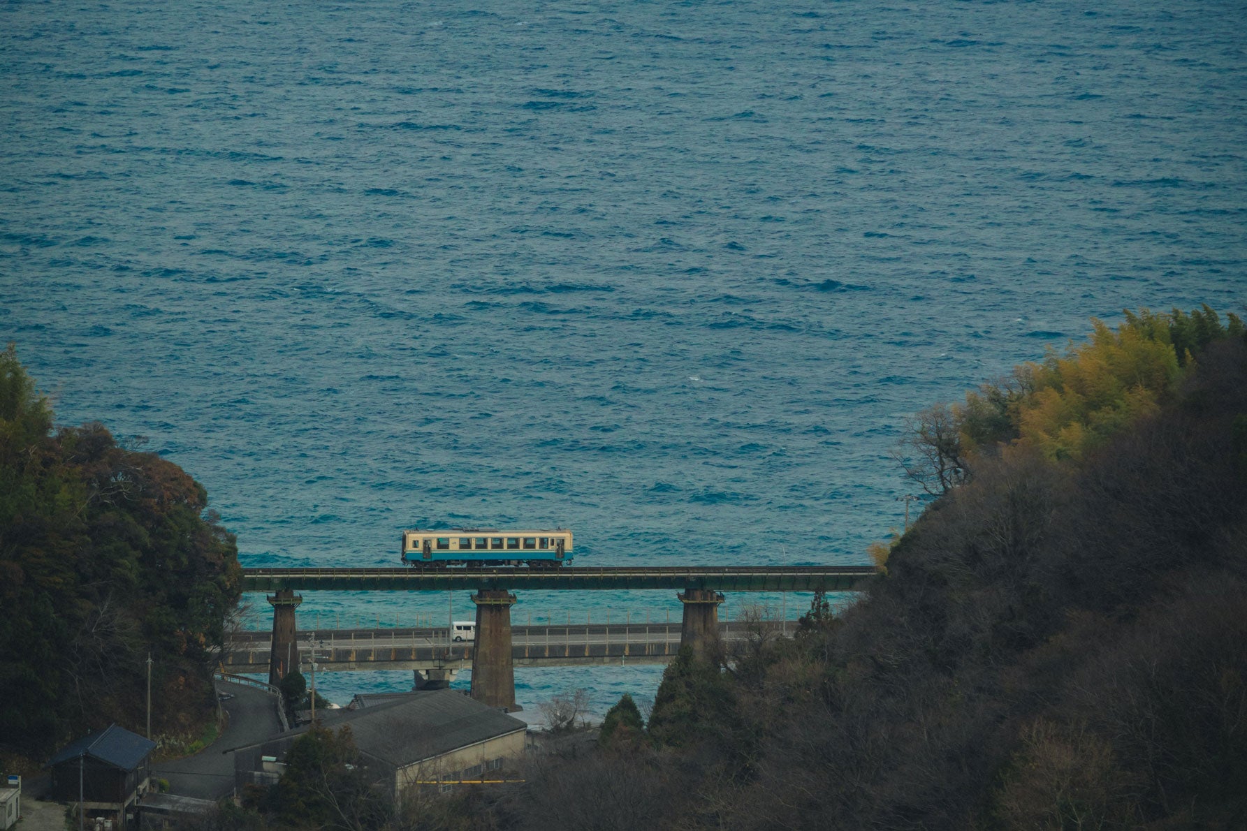 伊予灘を背景に、本村川橋梁を渡る一両編成の列車