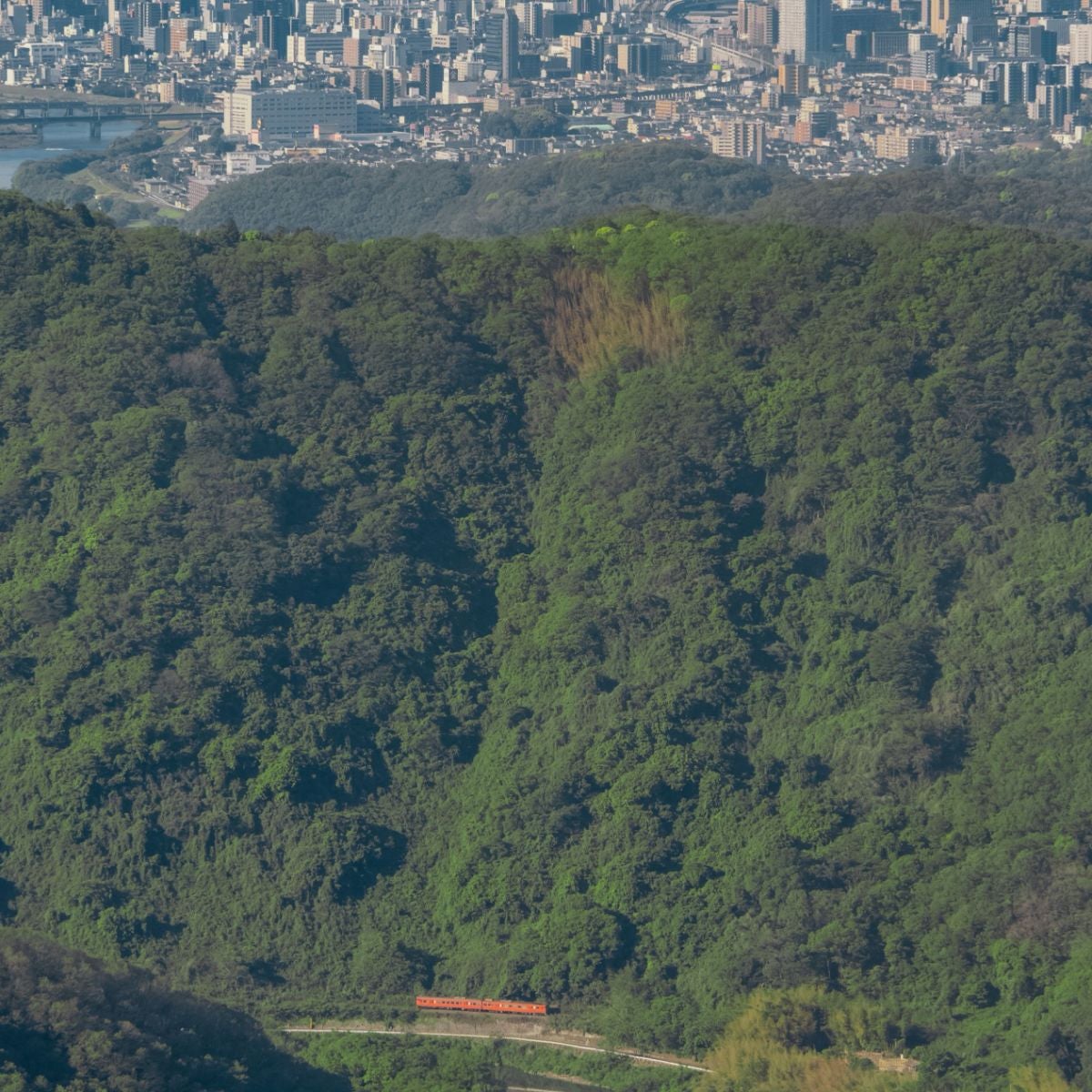 岡山市街地と山を挟んで走る列車