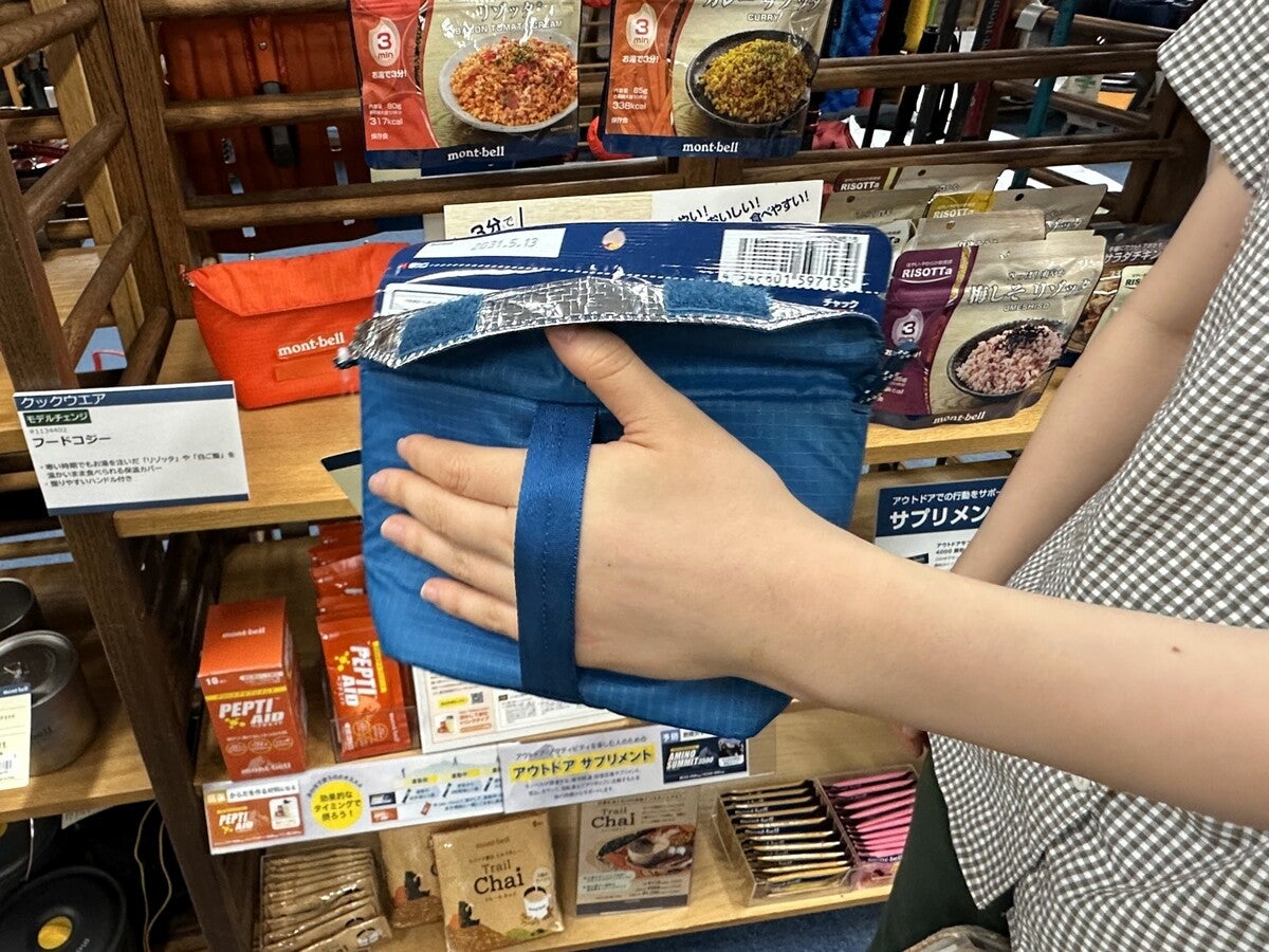 モンベル 手で持ってサイズ感を示しているブルーのコジー（保温ケース）
