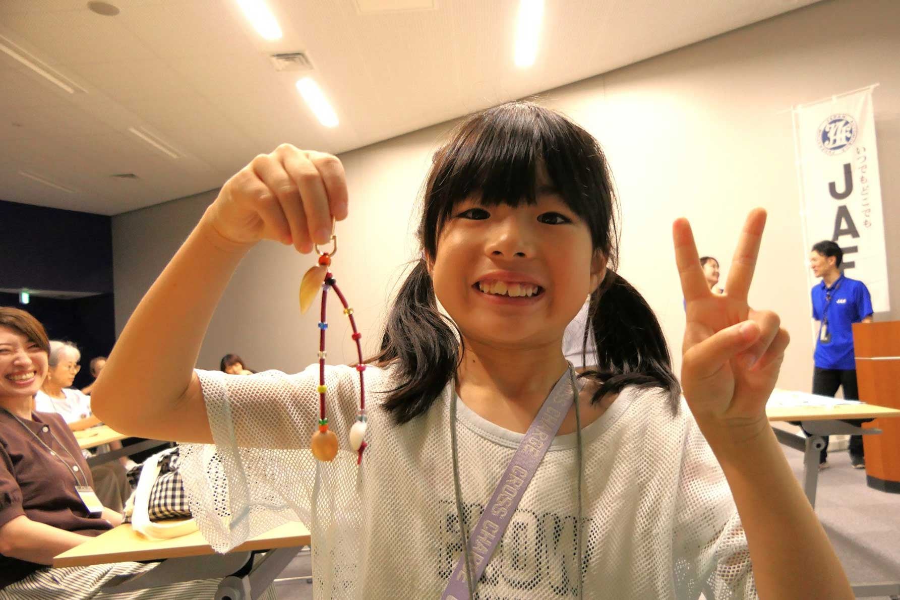 完成したオリジナルストラップを笑顔で披露する参加者。最高に素敵な笑顔