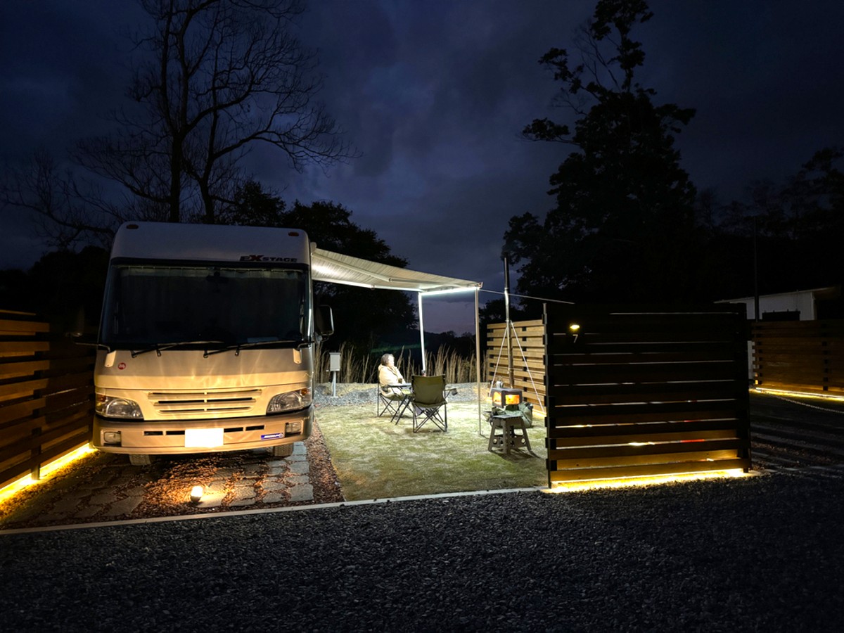 木柵に囲われ芝生スペースのあるRVパーク VISONのプライベートサイトの夜の風景