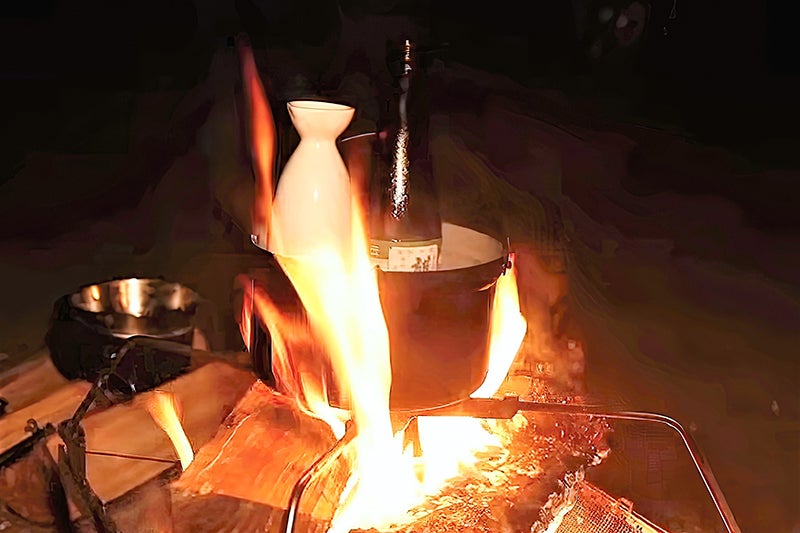 焚き火で熱燗を作る西村さん