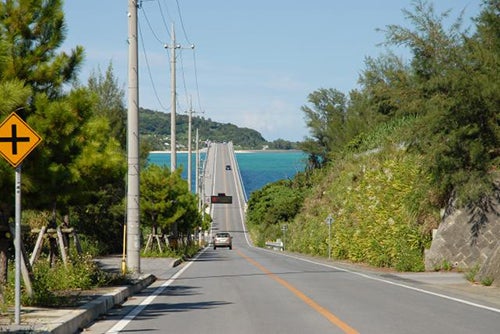 沖縄県の古宇利島へ渡る橋が見える直線道路