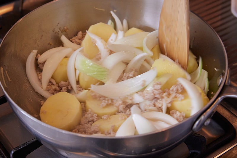 鍋でじゃがいもと玉ねぎとひき肉を炒める
